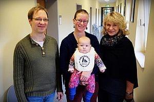 Eltern mit Baby und die Gleichstellungsbeauftragte der HSN stehen nebeneinander. Das Baby trägt das HSN-Lätzcen.
